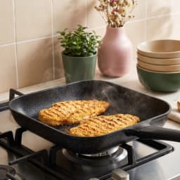 Black square granite grill pan with a long black handle and ridged cooking surface on a white background. - view 1