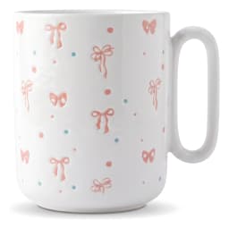White ceramic mug with pink bows and blue/red dots design, held in hand, light blue rim - view 2
