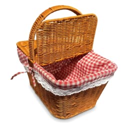 Brown woven picnic basket with red and white gingham lining, filled with grapes, cheese, bread, and a bottle, on a kitchen c… - view 2