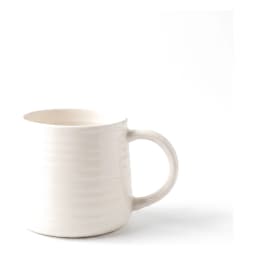 Single cream ceramic mug with horizontal ribbed texture and a handle, placed on a white shelf against a wooden background. - view 2