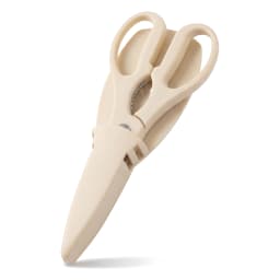 Beige silicone kitchen scissors with a matching protective sheath, lying on a white surface in a well-lit setting. - view 2