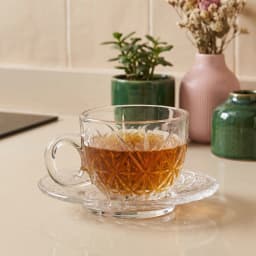 Clear glass cup with a diamond textured pattern and a matching glass saucer on a white background. - view 1