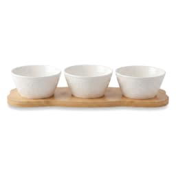 Three white porcelain serving bowls with embossed design on a light brown wood stand, filled with snacks and dip. - view 3