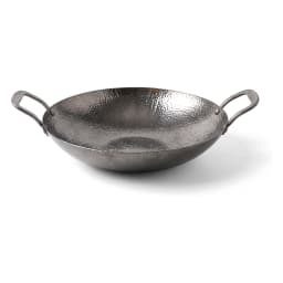 Small hammered dark grey metal wok filled with steaming stir-fried vegetables on a kitchen counter - view 2