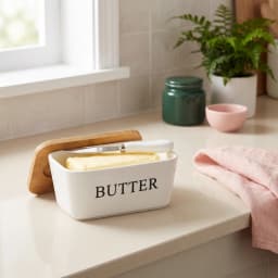 White rectangular porcelain butter dish with a light brown wooden lid and a white-handled butter knife resting in a slot. - view 1