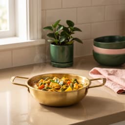 Steaming gold-tone stainless steel cooking pot with two handles, filled with chicken and vegetable curry on a kitchen counte… - view 1