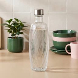 Clear glass bottle with a textured spiral pattern and a silver metal screw cap, shown on a white background. - view 1
