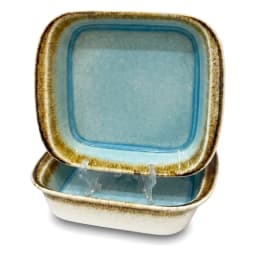 Two square porcelain baking dishes, one light blue and one off-white, with rustic brown rims, filled with steaming vegetable… - view 2