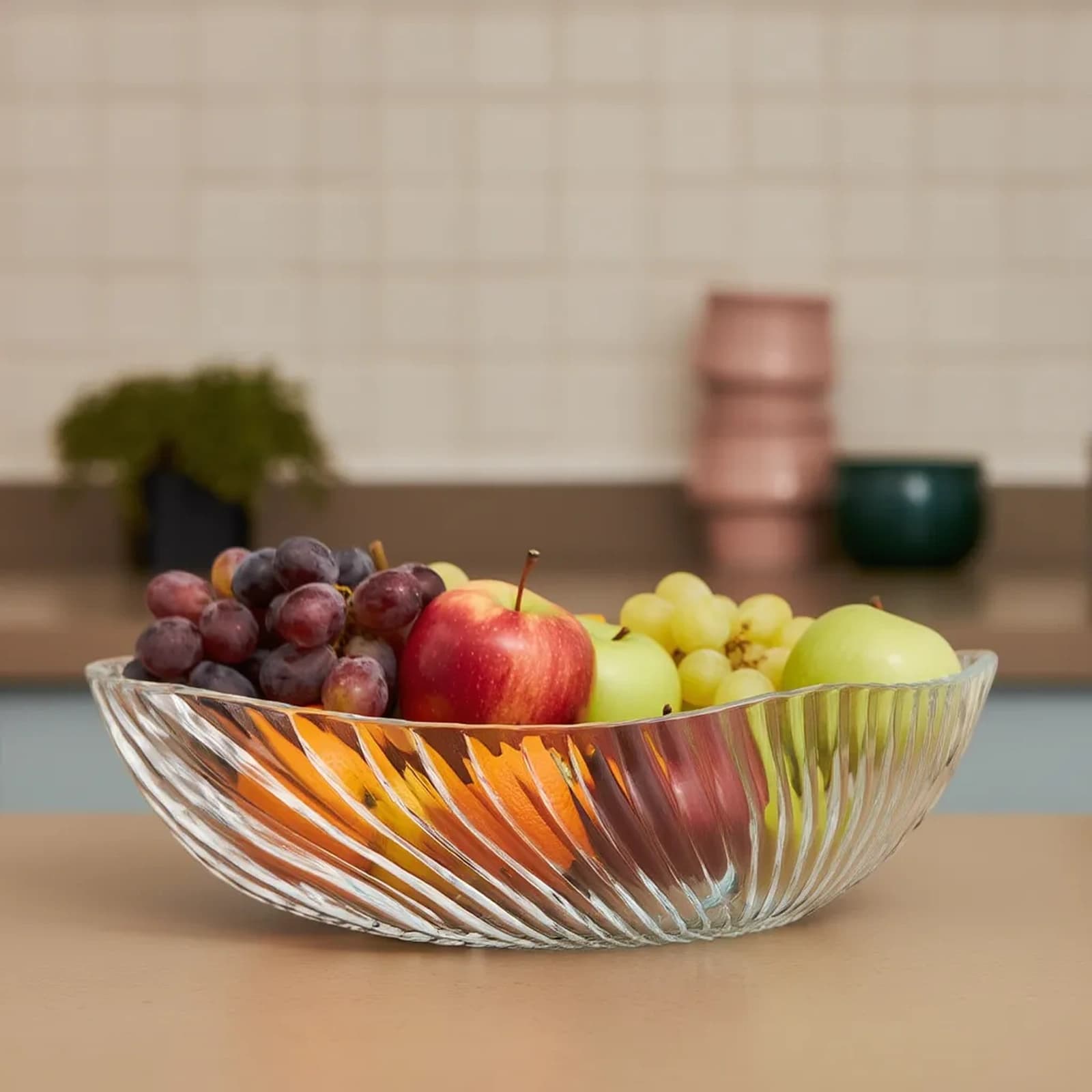 Clear glass serving bowl with a wavy rim and vertical ribbed texture, isolated on a white background.
