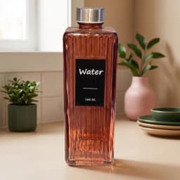Rose gold ribbed glass water bottle with a silver cap and black 'Water 1000 ML' label on a white shelf. - view 3