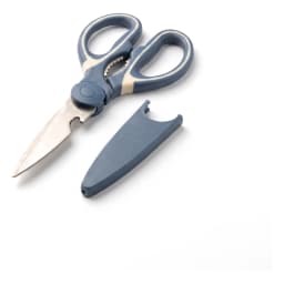 One pair of dark blue and cream silicone handle kitchen shears with serrated edge on a white shelf. - view 3