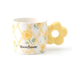 White ceramic mug with yellow sunflower pattern and yellow flower-shaped handle, held in a hand - view 2