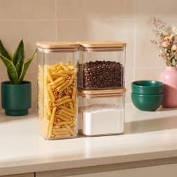 Three dark grey acrylic rectangular storage containers with light brown wooden lids on a white shelf. - view 1
