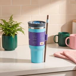 Aqua blue stainless steel tumbler with a dark lid, blue flip-top, and brown straw on a white surface. - view 1