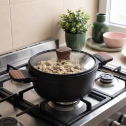 Black ceramic casserole pot with wood-look handles and lid, 22cm diameter, shown in packaging. - view 1