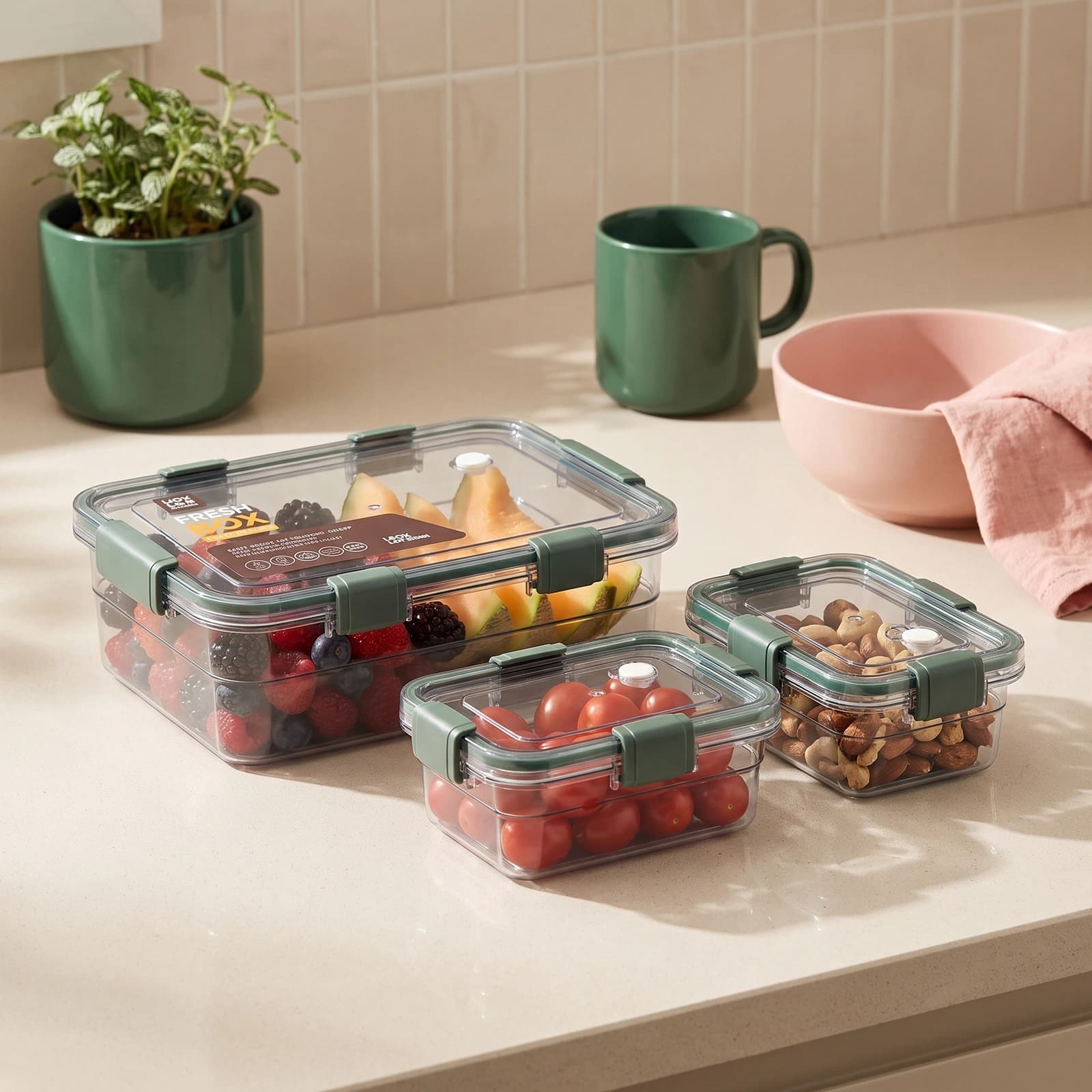 Three rectangular clear plastic food storage containers with dark green lids and locking clips on a white background.