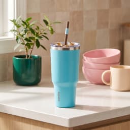 Aqua blue stainless steel tumbler with a dark lid, blue flip-top, and brown straw on a white surface. - view 4