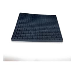 Dark gray square silicone coaster mat with a grid pattern, holding a steaming metal pot on a light brown kitchen counter. - view 2