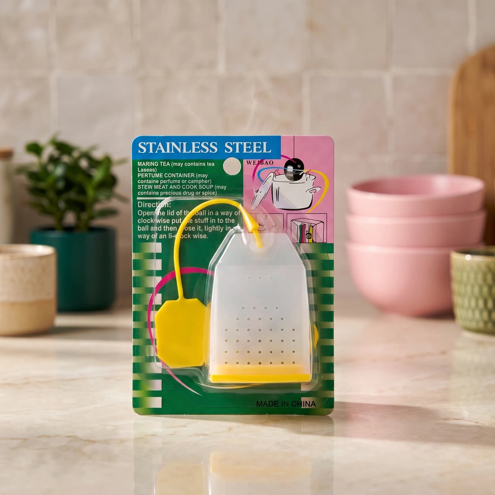 Single grey silicone tea infuser shaped like a tea bag with a yellow string and base, on a white background.