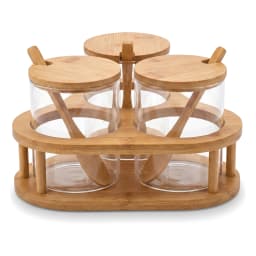 Three clear glass jars with light wood lids and spoons in a matching light wood stand on a white shelf. - view 2