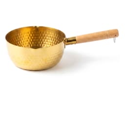 Golden hammered stainless steel milk pan with a light wooden handle, containing a clear liquid with star anise and cinnamon… - view 2