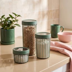 Set of three dark grey translucent acrylic storage jars with vertical ridges and opaque black lids on a white background. - view 1
