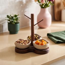 Dark brown wooden serving stand with three light beige porcelain bowls, wavy shape, on a white background. - view 1