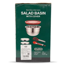 Stainless steel mixing bowl with red whisk and red lid on a light kitchen counter, next to a pink potted plant. - view 2