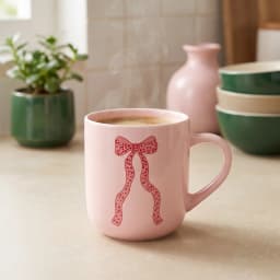Light pink ceramic mug with a red polka-dotted ribbon design on a white background - view 1