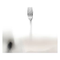 Single silver and gold stainless steel dinner fork with a curved handle, isolated on a clean white background. - view 2