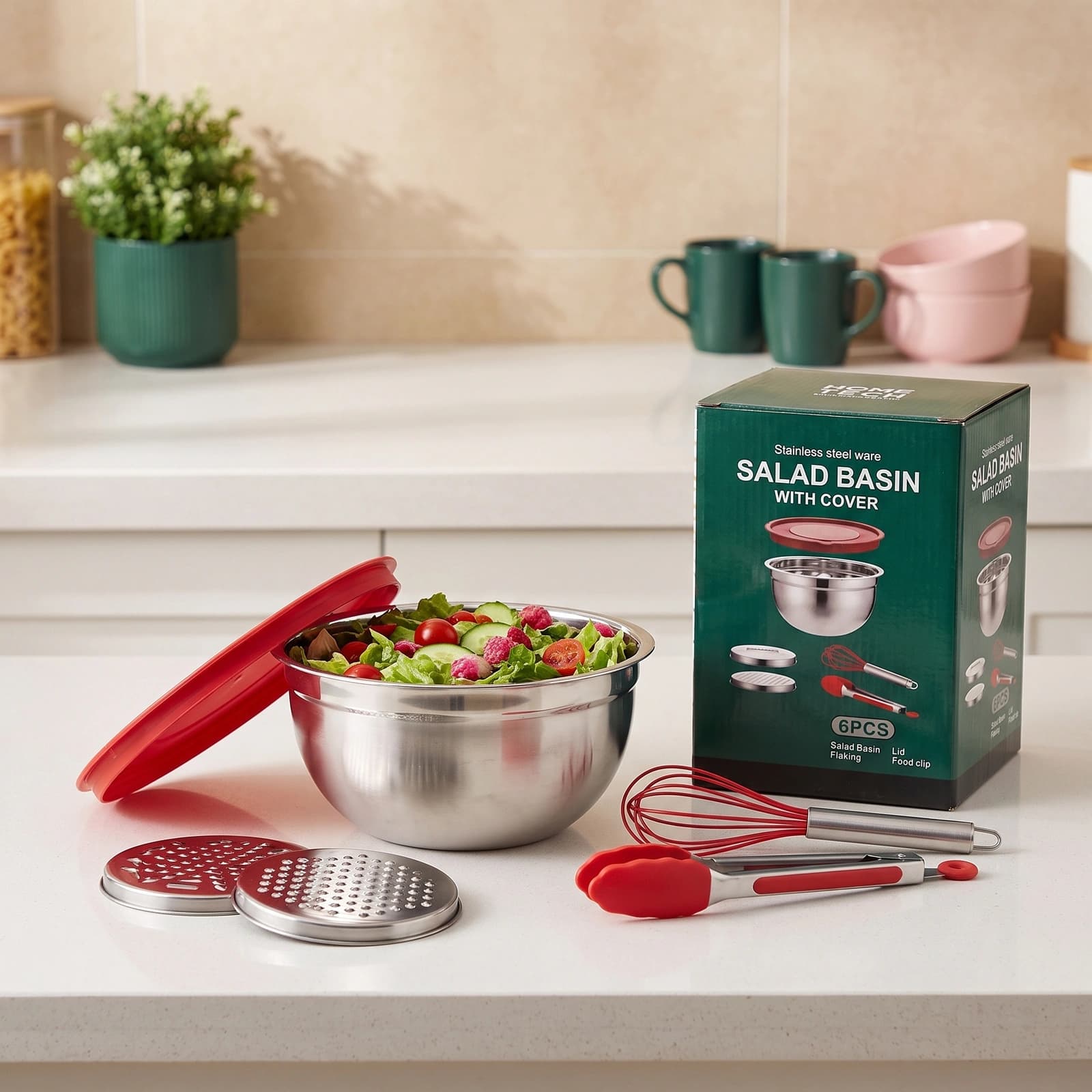 Stainless steel mixing bowl with red whisk and red lid on a light kitchen counter, next to a pink potted plant.