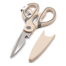 Beige and dark grey silicone kitchen scissors with metallic blades and a matching beige blade cover on a white shelf. - view 2